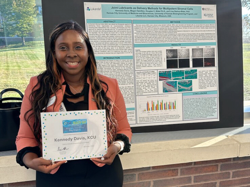 Kennedy Davis Recognition receiving award in front of her poster.